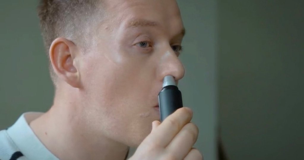 Man using nose hair trimmer to trim his nose hair