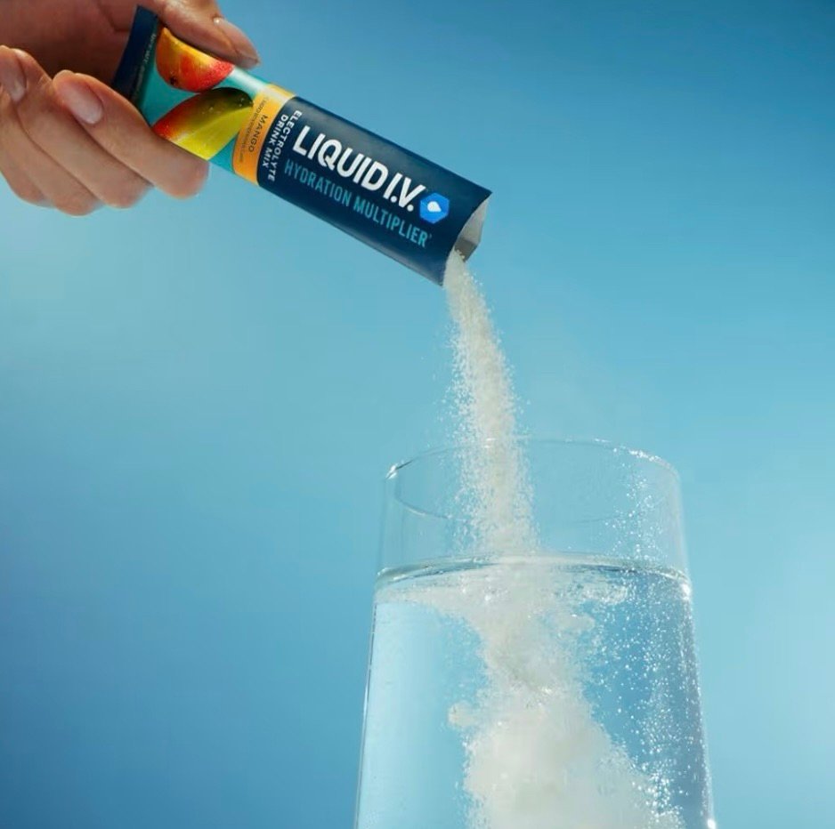 Liquid IV being dumped into a cup of water to help with hydration after surgery